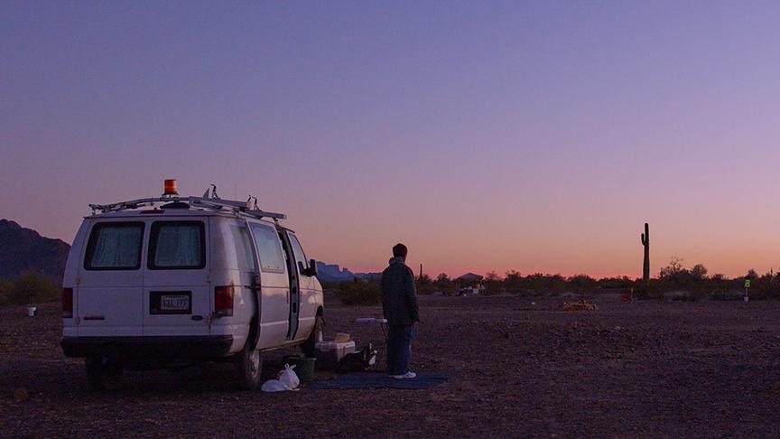 Frau vor einem Campervan bei Dämmerung