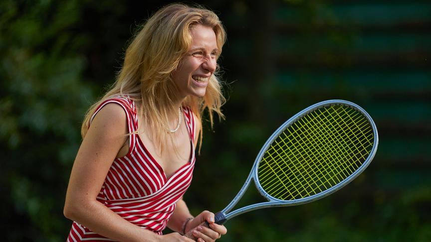 © Foto: ORF/Bravado Media/MarVista Entertainment/Umberto Poto Frau lächelt und hält einen Tennisschläger in den Händen.