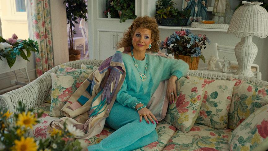 Eine Frau in einheitlich türkiser Kleidung sitzt auf einem Sofa.