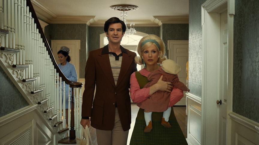 Eine Frau mit Kind auf dem Arm und ein Mann gehen nebeneinander durch den Flur eines Hauses.