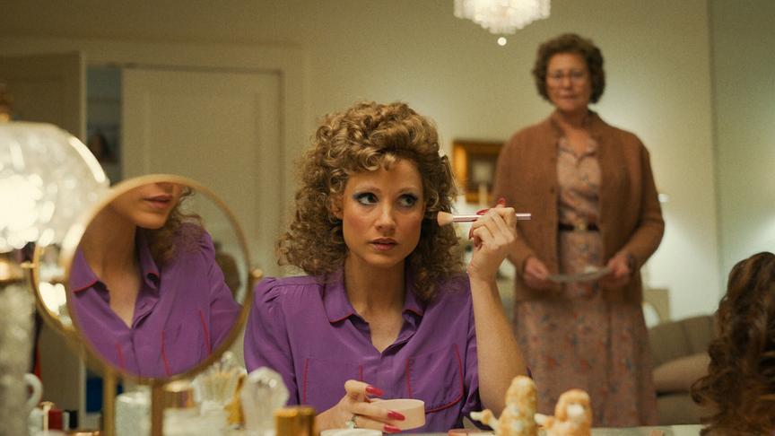 Eine Frau schminkt sich während hinter ihr eine andere Frau steht.