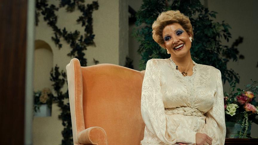 Eine Frau sitzt lachend auf einem Sessel.