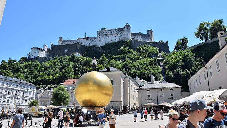 Hinter dem Salzburger Dom befindet sich der Kapitelplatz mit einem herrlichen Blick auf die Festung Hohensalzburg. Die goldene Kugel, auch Sphaera genannt, ist ein Kunstwerk von Stephan Balkenhol. Umgangssprachlich wird sie auch Balkenhol Mozartkugel genannt.