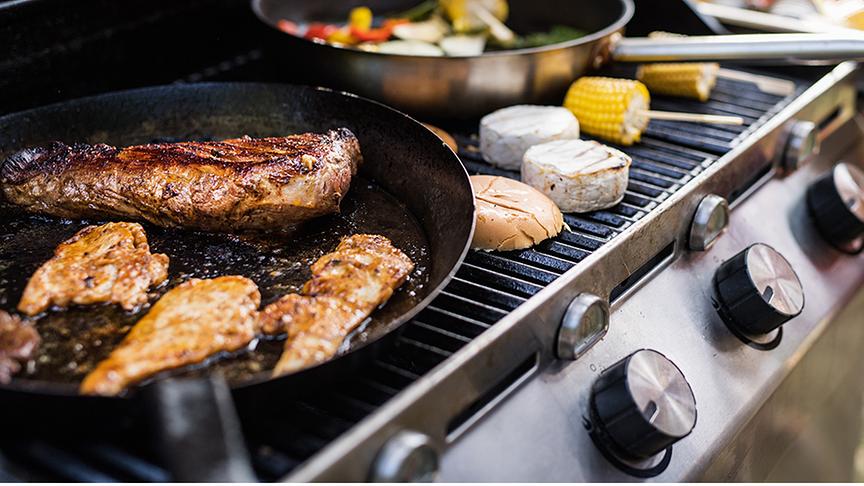 Ein Grill auf dem Fleisch, Gemüse und Käse liegen