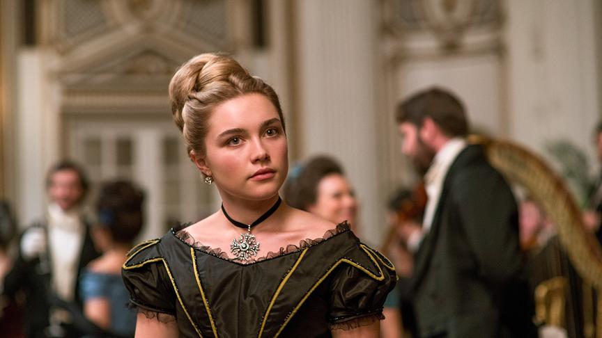 Ein Mädchen in einem Ballkleid in einem Raum mit weiteren Personen in Abendgarderobe