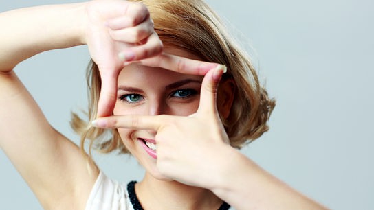 © Colourbox Eine junge Frau sieht durch ihre Finger.