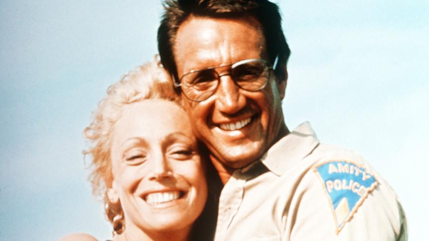 Mann und Frau halten sich dicht umschlungen in den Armen und lachen in die Kamera