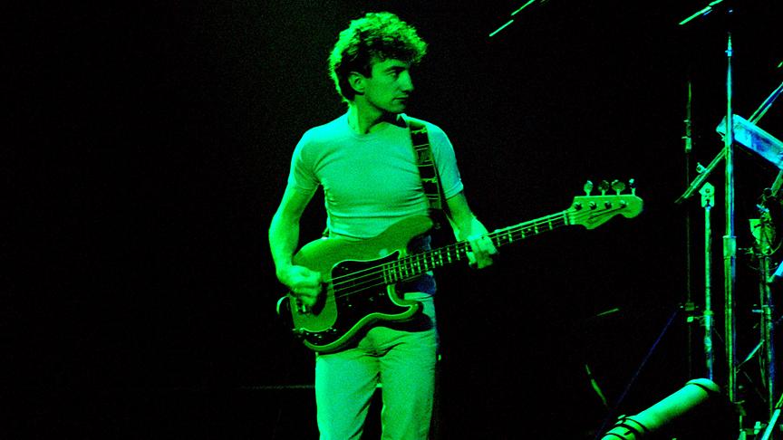 John Deacon an der Gitarre und in grünes Licht getaucht.