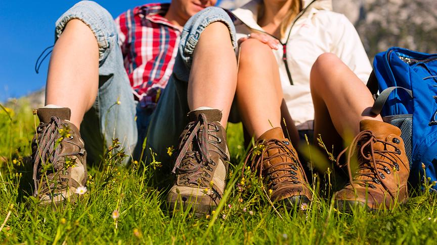 Ein Pärchen macht eine Wander-Pause und sitzt in der Wiese.