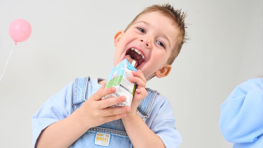 Ein Bub mit einem Getränkepäckchen von PURE&FUN