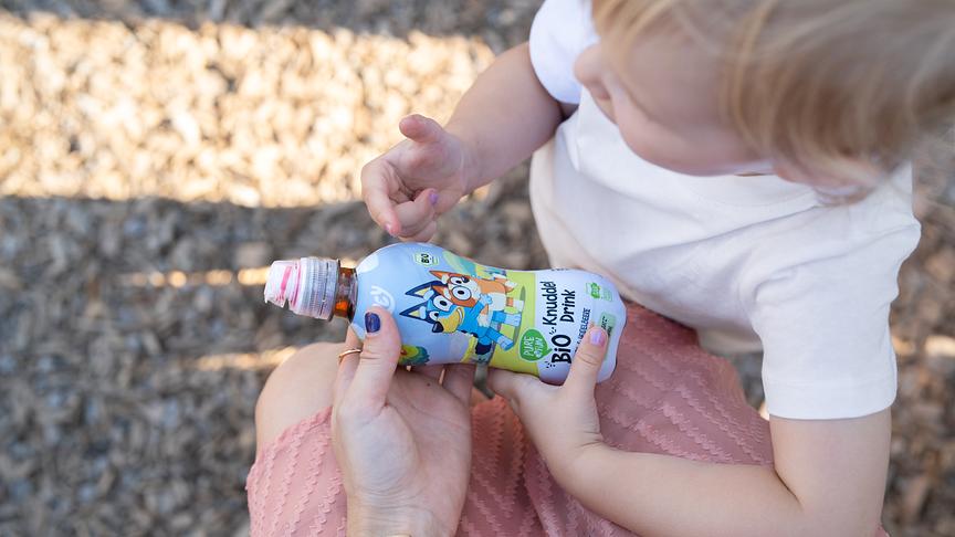 Eine Mutter bietet ihrer kleinen Tochter ein Getränk von PURE&FUN an.