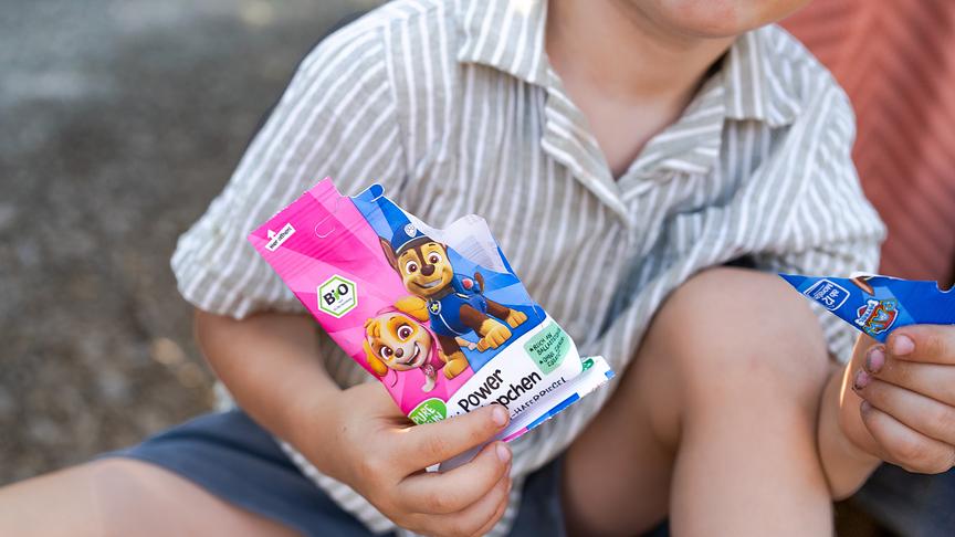 Ein Bub öffnet eine Knabbertüte von PURE&FUN.