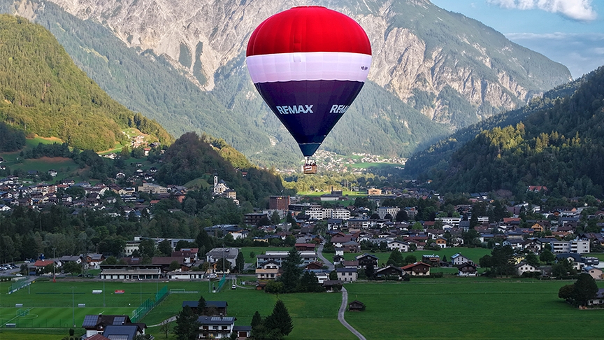 Ein REMAX-Ballon schwebt über der Landschaft.