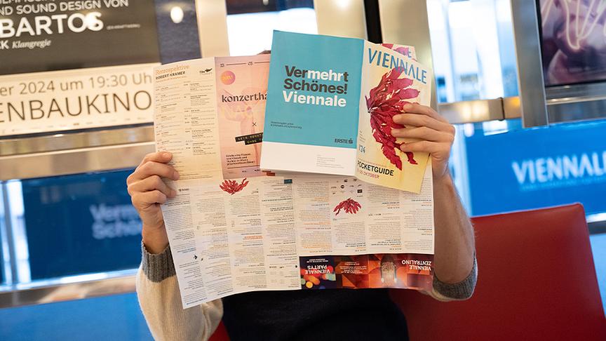 Ein Besucher hält Infofolder der Viennale in den Händen.