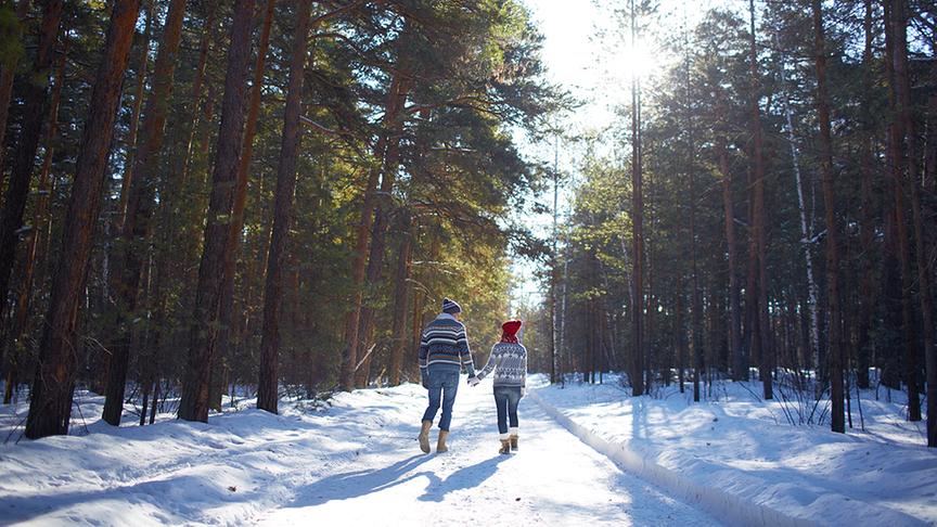 Ein Pärchen geht im schneebedeckten Wald spazieren.