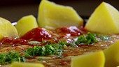 Faschierte Bällchen gefüllt mit Käse in Tomatensauce im Rohr gebacken, dazu Kartoffel