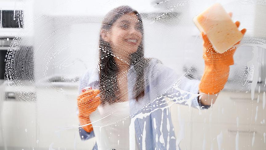 Eine Frau putzt Fenster mit einem Schwamm.