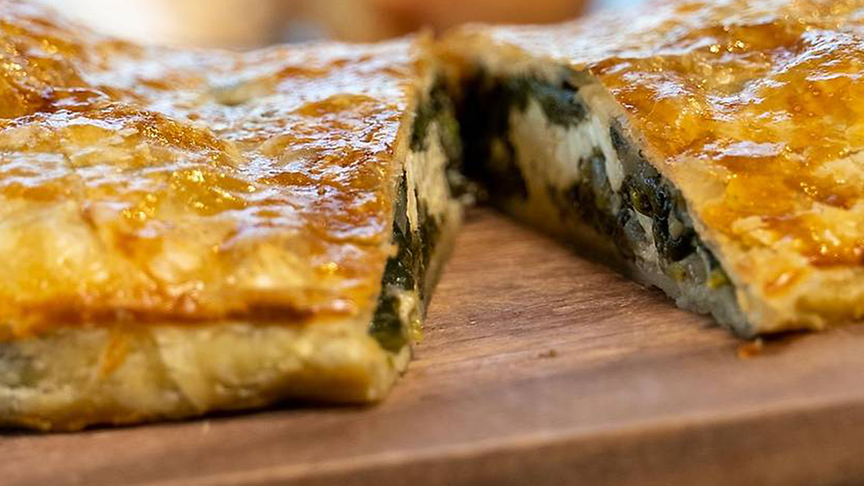 Spinat Feta Strudel in der Mitte aufgeschnitten auf einem Holzbrett
