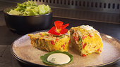 Goldbraun gebackene Ofen-Palatschinke, aufgerollt mit Frischkäse, frischem Gemüse und Hühnerstreifen, dazu Knoblauch-Dip und grüner Salat.