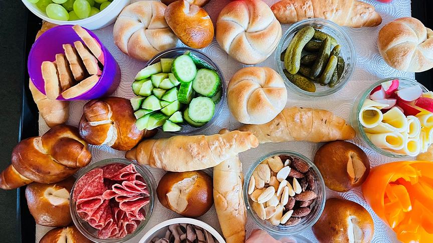 Snackboard mit Jourgebäck, klein geschnittenem Obst und Gemüse und Nüssen.