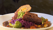 Kross gebratene vegane Seitan-Rouladen mit würziger Gemüsefüllung, serviert mit dunkler Bratensauce aus Wurzelgemüse.