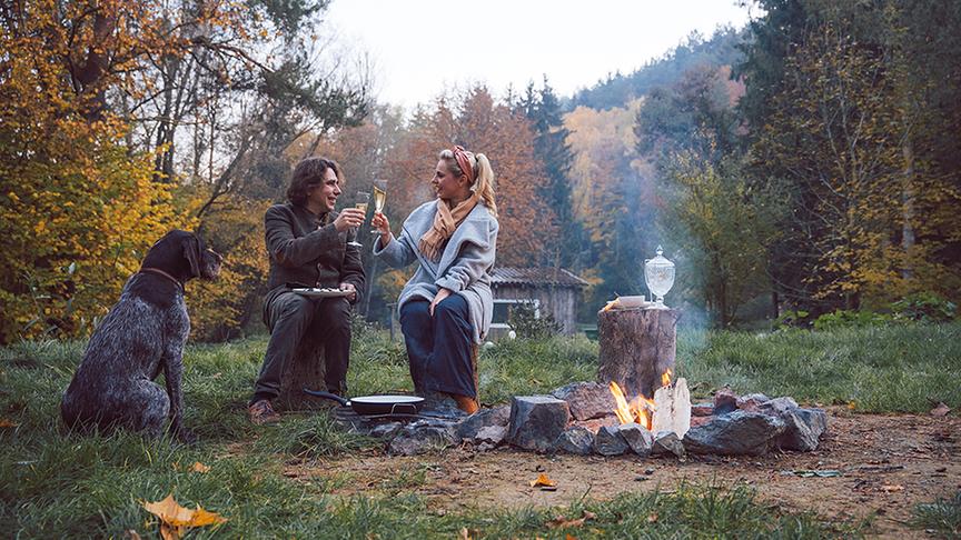 Silvia und Romeo Schermann genießen ihr Essen bei einem Lagerfeuer.