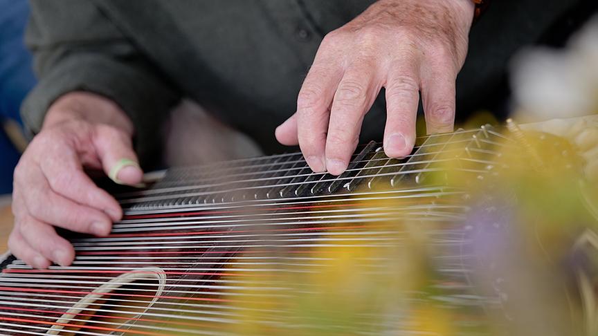 Gottlied Jehle spielt Zither bei einer Hütte auf der Larein Alpe.