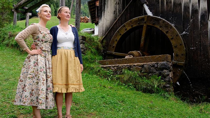 Silvia Schneider und Esther Lugger stehen vor einer Wassermühle.