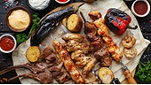 Grillplatte mit Melanzani, einer Auswahl an Fleischspießen, Kartoffeln, Paprika und Champignons