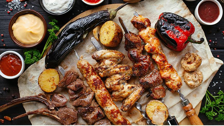© Unsplash (Beispielfoto) Grillplatte mit Melanzani, einer Auswahl an Fleischspießen, Kartoffeln, Paprika und Champignons