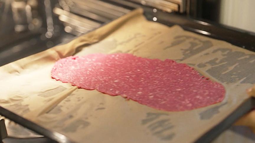 Das Faschierte wird zwischen zwei Backpapierbögen flach ausgerollt und knusprig gebacken.