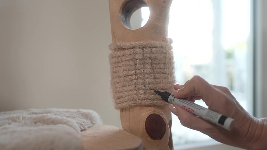 © Foto: ORF Eine Person malt mit einem Stift vertikale Striche auf den Kratzbereich eines Kratzbaumes, die Katzenkratzspuren imitieren.
