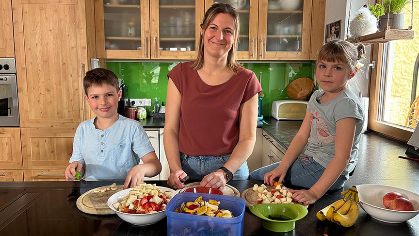 Laurin, Andrea und Romina schneiden Futter für ihre Familien-Wurmkiste.