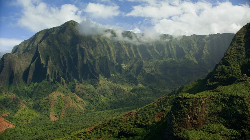 Im Bild: Landschaftlich beeindruckend und vom Regenwald überzogen sind die vulkanischen Berghänge der Nā Pali Küste auf Kauai.