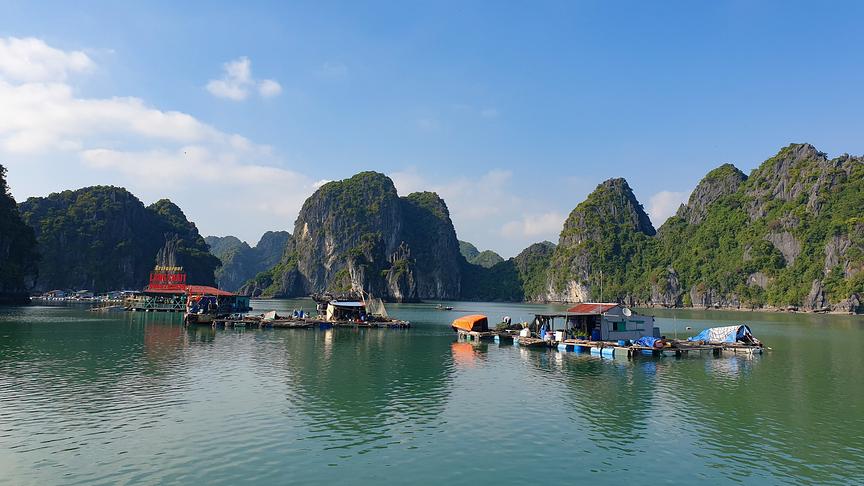 Eine Bucht mit schwimmenden Bauten und steil-abfallenden Bergen.