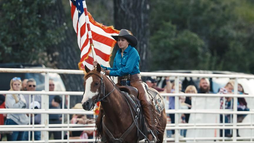© Foto: ORF/LE CINQUIEME REVE Eine Frau mit Hut reitet auf einem Pferd mit einer großen Flagge in der Hand.