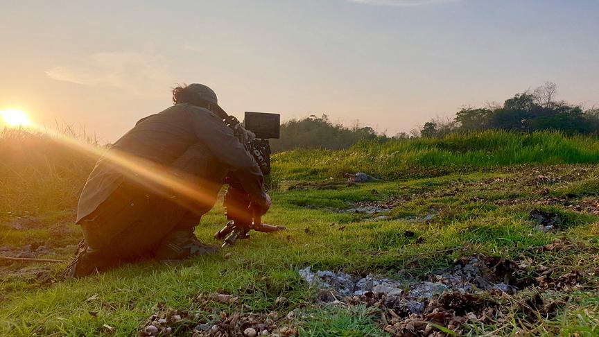 Ein Kameramann bei der Arbeit im grünen Gelände.