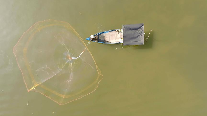 Fischerboot mit ausgeworgenem Netz von oben.