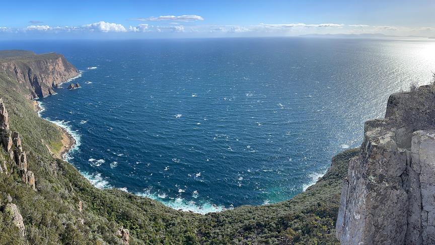Bucht an einer steil abfallenden und teils bewachsenen Küste