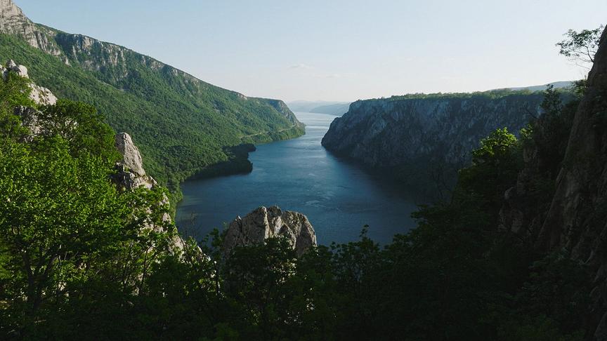Breite Schlucht mit bewaldeten, steil abfallenden Hügeln links und rechts und der Donau in der Mitte.