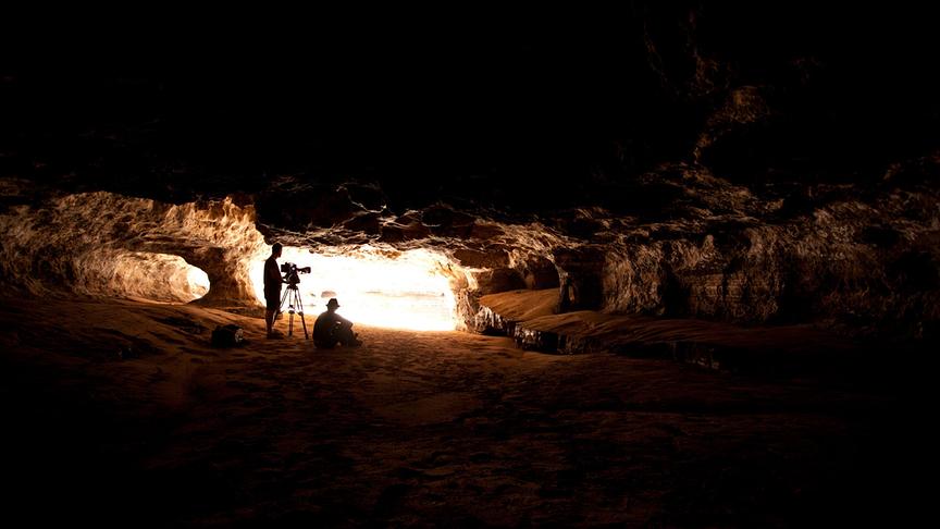 Das Kamerateam in einer dunklen, großen Höhle.
