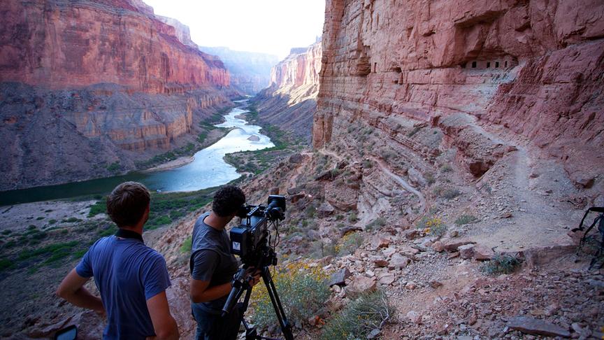 Zwei Personen mit einer Stativkamera filmen im roten Canyon.