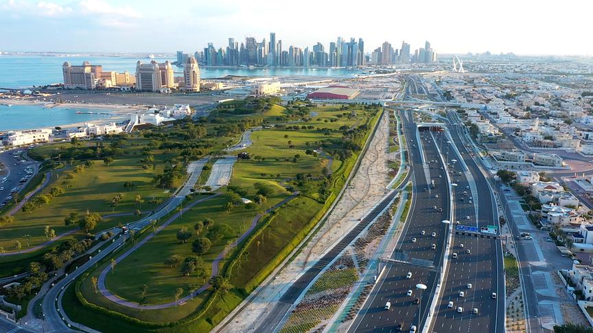 © Foto: ORF/Skyland Productions/Qatar Tourism Großstadt mit Hochhaus-Skyline im Hintergrund, mehrspuriger Straße und Park