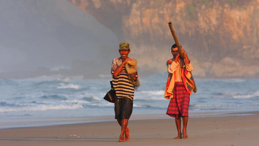 Zwei Einheimische am Strand gehend.