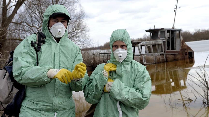 Eine Frau und ein Mann in Schutzkleidung vor einem See