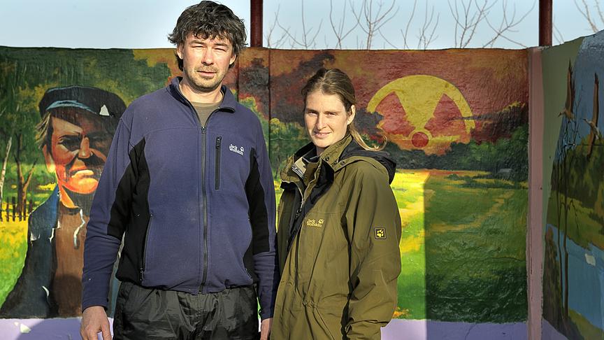 Ein Mann und eine Frau vor einem Banner mit radiokativem Symbol