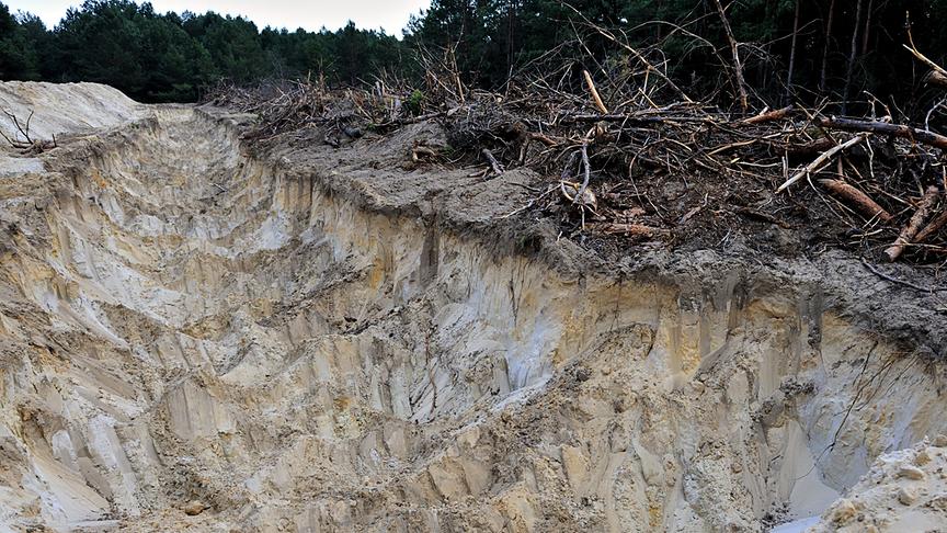 Tiefe Grube neben der abgestorbenes Holz liegt