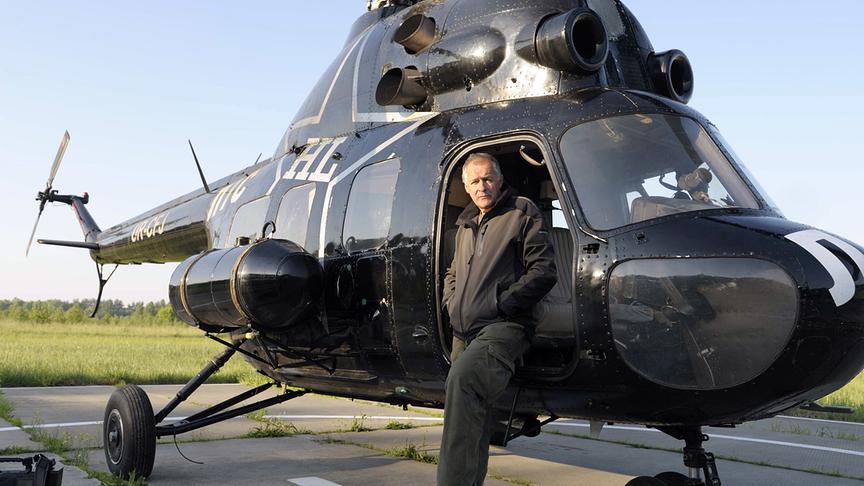 Mann an einem Hubschrauber lehnend