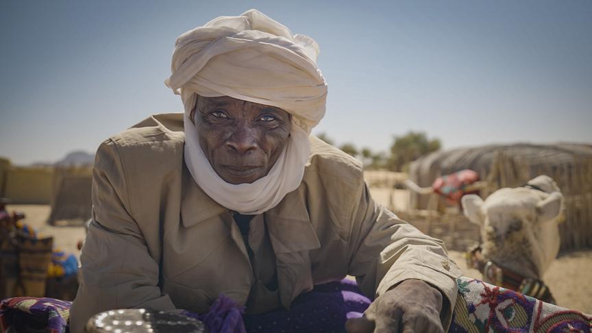 Mann mit weißem Turban in der Wüste.