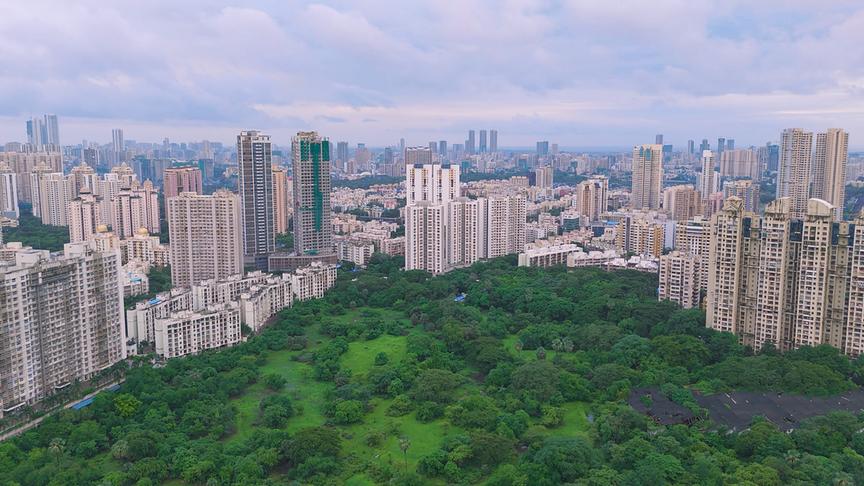 Hinter einer Grünfläche erstrecken sich die Hochhäuser der Metropole Mumbai.